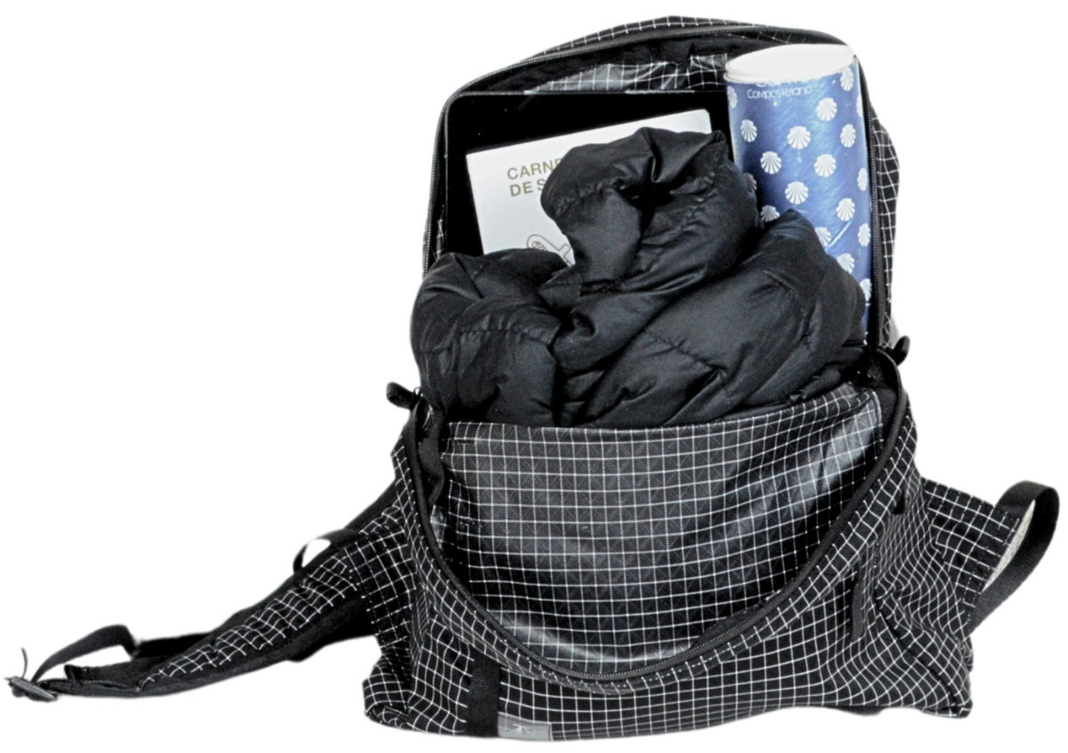 The Mighty Mini Unisex Backpack with items inside of puffy coat, pilgrim's Compostela, iPad, and Carnet de Pelerin.