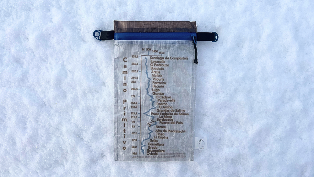 Ultreiatrek Dyneema® Valuables Holder with Camino Primitivo Elevation Gain and Kilometers. It is placed on a snowy background