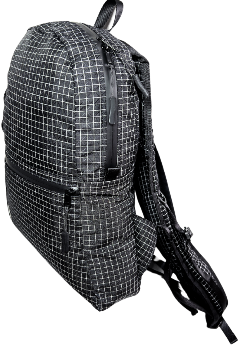 Side View of the Mighty Mini Unisex Backpack. Black fabric with white Dyneema® reinforcement creates rectangular boxes. Pocket with matte HHH zipper shown on front. Webbing with slots for a handkerchief or carabiner. 