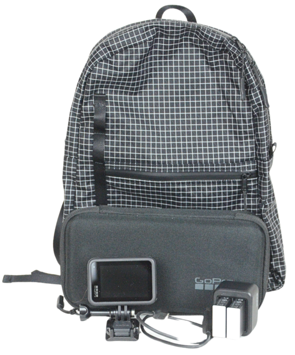 The Mighty Mini Unisex Backpack with a GoPro Camera, Case, and Batteries in front of it.