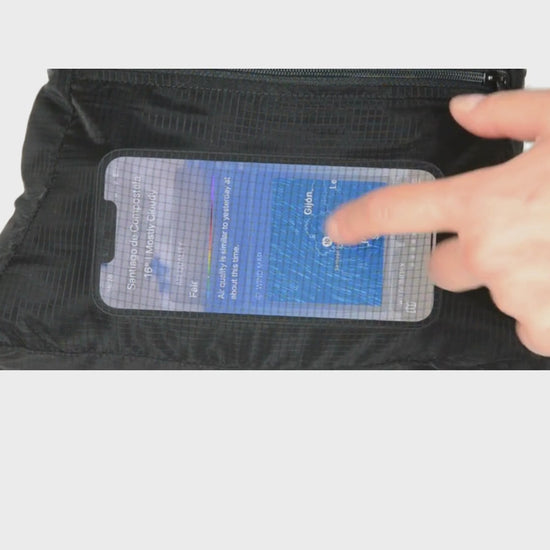 Touchscreen. Front pocket of the unisex MINImalist backpack. It is black in color and made of sheer nylon fabric. Hand touches phone through fabric and scrolls on weather details in Galicia.